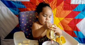 First Nations Child in a highchair eating fruit